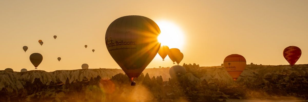 Hot air balloon rising with sunrise in Cappadocia valleys, Turkey | Conmigo Travel Agency